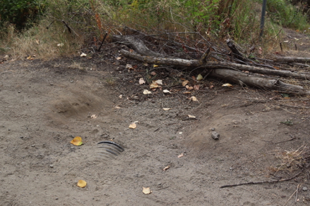 Rut in compacted gravel trail – corrugated pipe and logs on the side